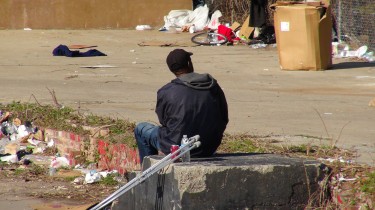 Homeless man sits alone with his crutch at his side and the tent where other home lives sits across from him. Downtown Atlanta on Peach & Pine 3/4/14